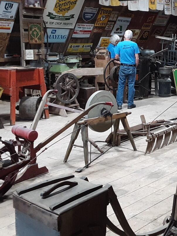 A collection of antique farm machines and advertising signs on display.